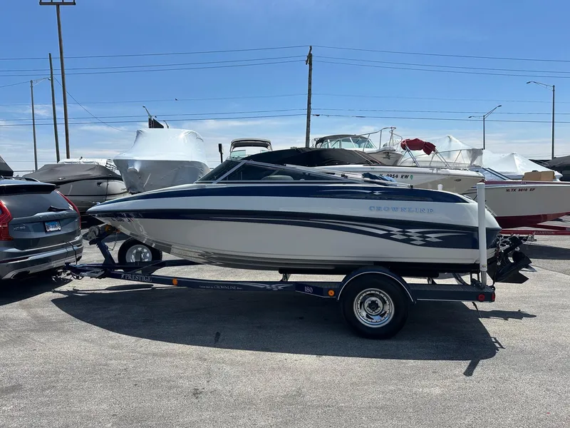 Slide: The Image of 2002 Crownline 180 BR boat on trailer in parking lot, side view. - 2