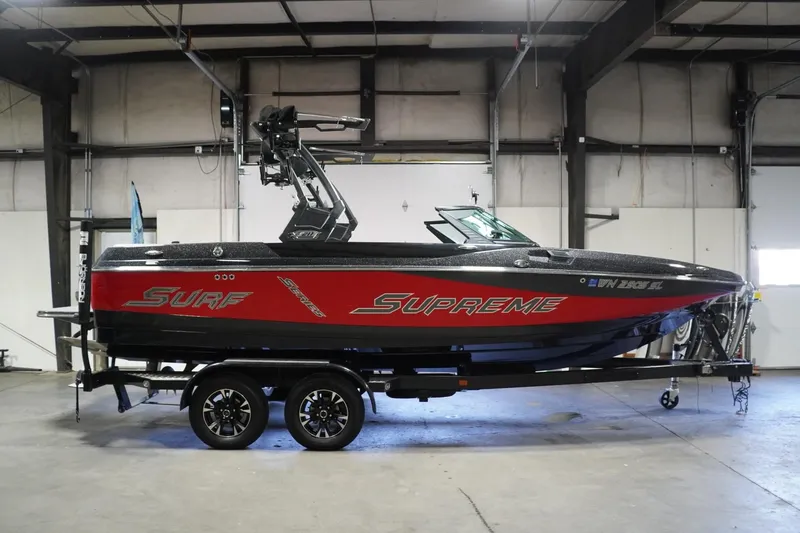 Slide: The Image of 2017 Supreme S211 boat in a warehouse, red and black design, on a trailer. - 1