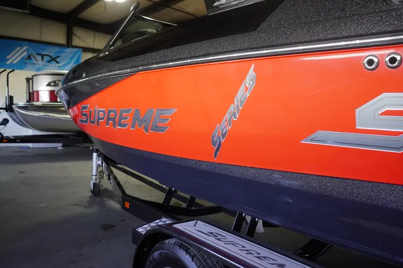 Slide: The Image of 2017 Supreme S211 boat with vibrant orange detailing in a showroom. - 10
