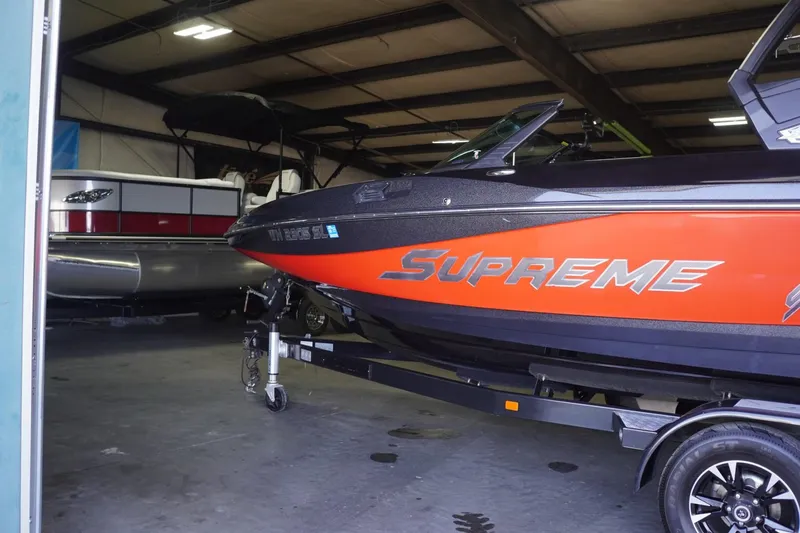 Slide: The Image of 2017 Supreme S211 boat in storage, featuring vibrant orange and black design. - 18