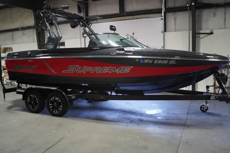 Slide: The Image of 2017 Supreme S211 boat in a garage, featuring a sleek black and red design. - 2