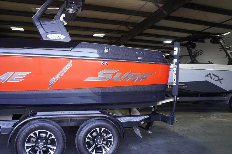 Slide: The Image of Red and black 2017 Supreme S211 boat with "Surf" branding in a warehouse. - 20