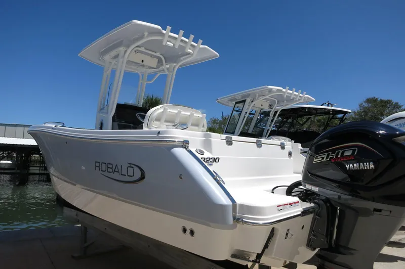 Slide: The Image of 2025 Robalo R230 Center Console boat with Yamaha engine, docked under clear blue sky. - 1