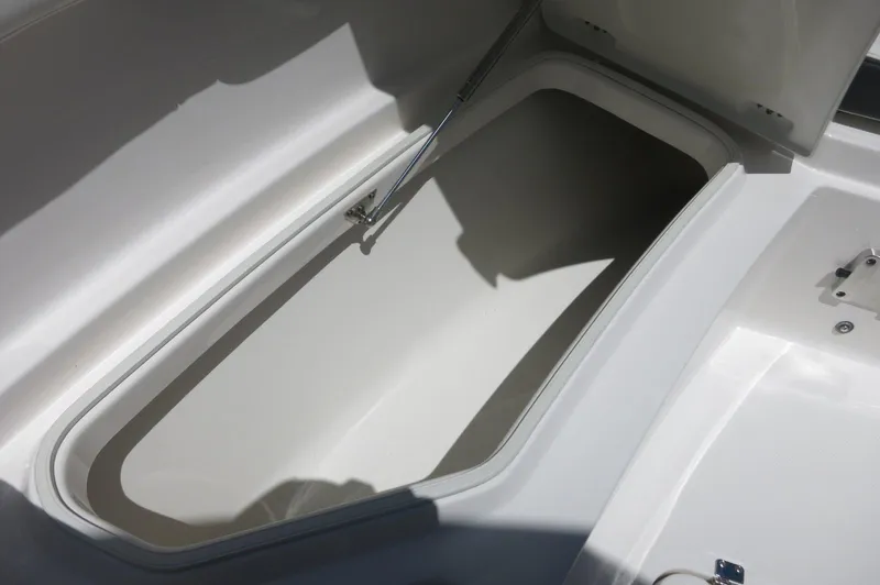 Slide: The Image of 2025 Robalo R230 Center Console storage compartment, open lid, white interior. - 11