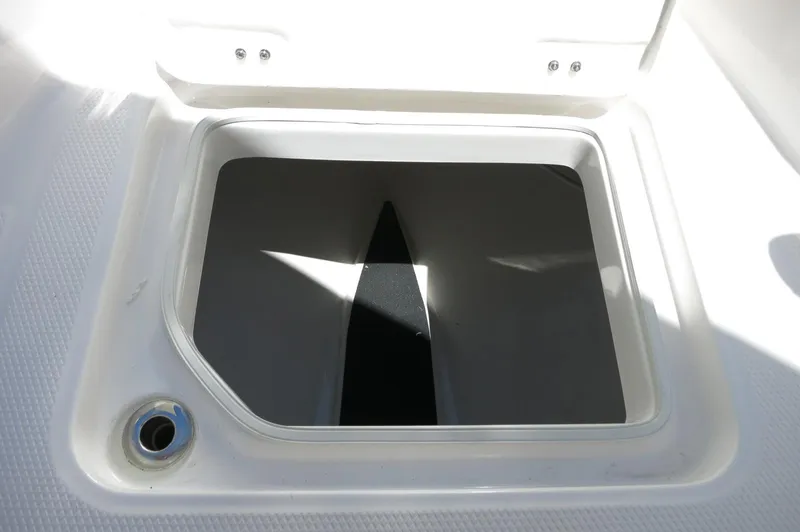 Slide: The Image of 2025 Robalo R230 Center Console storage compartment, open lid, white interior. - 13