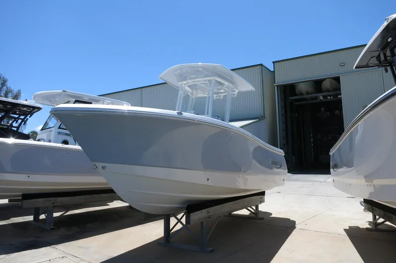 Slide: The Image of 2025 Robalo R230 Center Console boat displayed outdoors near a warehouse. - 2