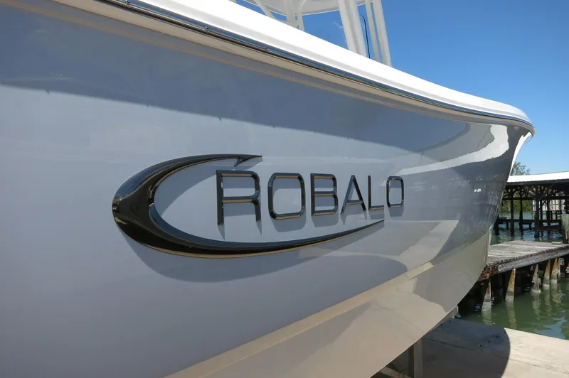 Slide: The Image of 2025 Robalo R230 Center Console boat docked, showcasing sleek design and logo. - 3