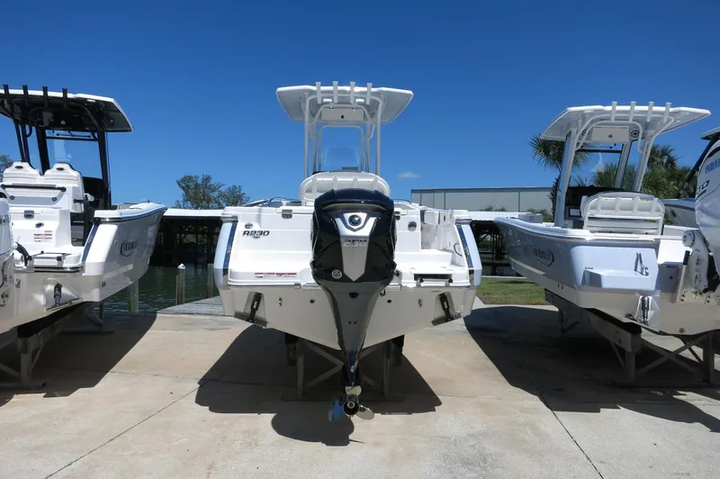 Slide: The Image of 2025 Robalo R230 Center Console boat displayed outdoors, rear view, with clear blue sky. - 6
