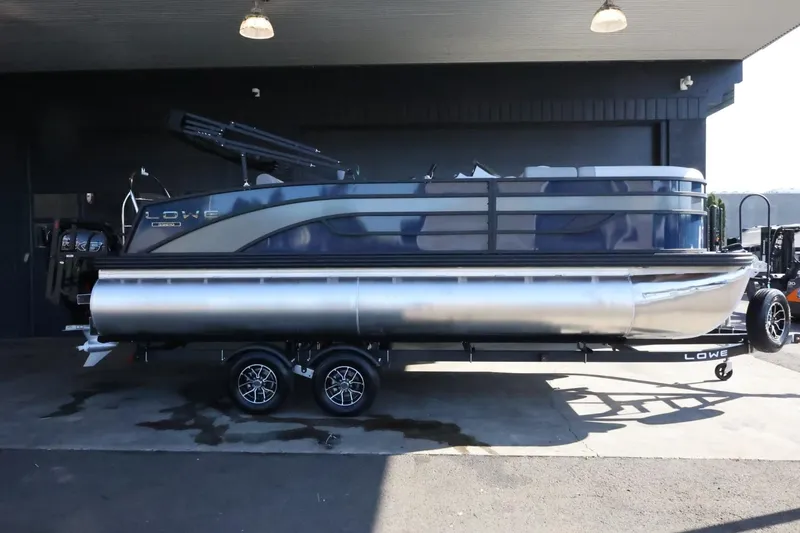 Slide: The Image of 2025 Lowe SS 210 DL pontoon boat on trailer, parked in a garage. - 1