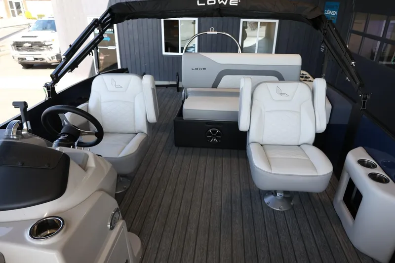 Slide: The Image of 2025 Lowe SS 210 DL pontoon boat interior with plush seating and modern helm. - 14