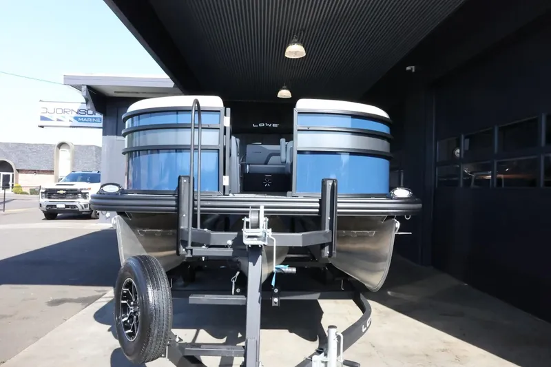 Slide: The Image of 2025 Lowe SS 210 DL pontoon boat on trailer, parked outside a building. - 3