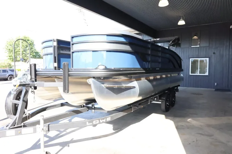 Slide: The Image of 2025 Lowe SS 210 DL pontoon boat on trailer in covered area. - 4