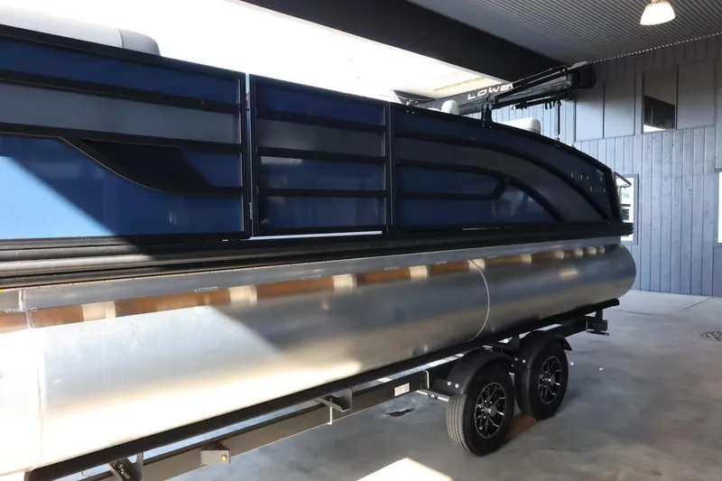 Slide: The Image of 2025 Lowe SS 210 DL pontoon boat on trailer in covered storage area. - 5