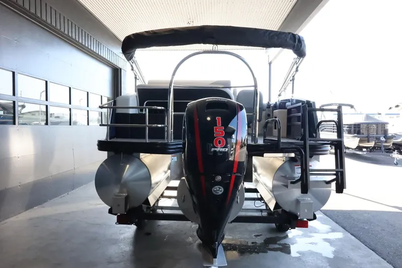 Slide: The Image of 2025 Lowe SS 210 DL pontoon boat with powerful 150 HP engine, docked under shelter. - 7