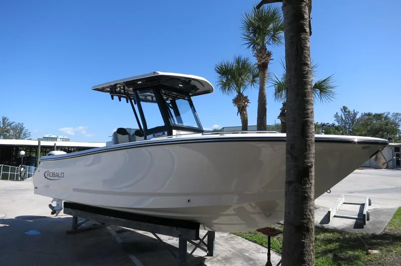Slide: The Image of 2025 Robalo R250 Center Console boat on display, sunny day, palm trees in background. - 2