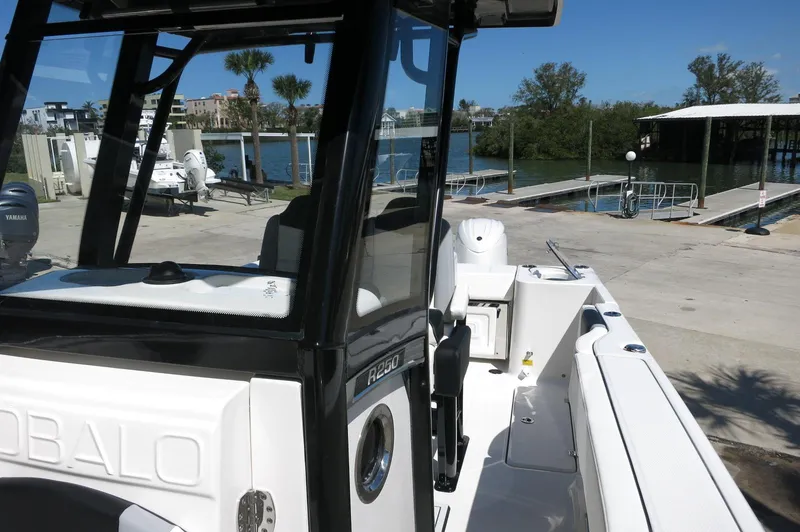 Slide: The Image of 2025 Robalo R250 Center Console boat docked near a marina with clear skies. - 29