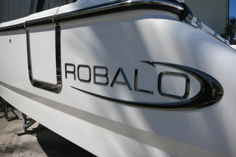Slide: The Image of 2025 Robalo R250 Center Console boat, close-up of logo on white hull. - 6