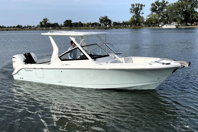 Slide: The Image of 2025 Edgewater 262 CX boat cruising on a calm lake with trees in the background. - 1