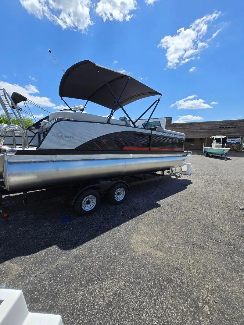 Slide: The Image of 2025 Quest 22rls pontoon boat with canopy on trailer, parked outdoors under blue sky. - 16