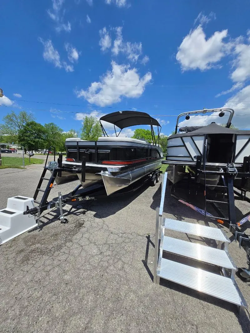 Slide: The Image of 2025 Quest 22rls pontoon boat on trailer under blue sky. - 2