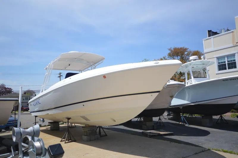 The Image of 2004 Intrepid 323 Cuddy boat on display, elevated on stands, under clear blue sky. - 1