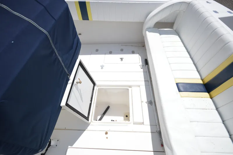Slide: The Image of 2004 Intrepid 323 Cuddy boat interior with open storage compartment and cushioned seating. - 12