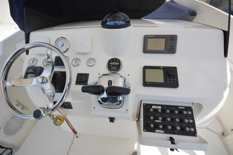Slide: The Image of 2004 Intrepid 323 Cuddy helm with steering wheel, gauges, and navigation controls. - 13