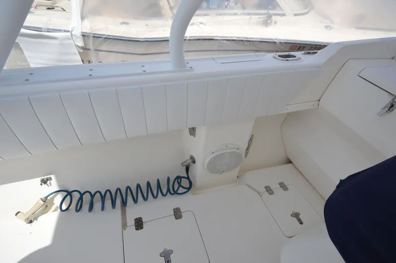 Slide: The Image of 2004 Intrepid 323 Cuddy interior with storage compartments and coiled hose. - 18
