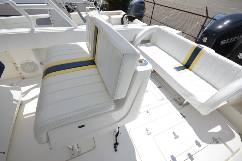 Slide: The Image of 2004 Intrepid 323 Cuddy boat interior with white seating and blue-yellow accents. - 19