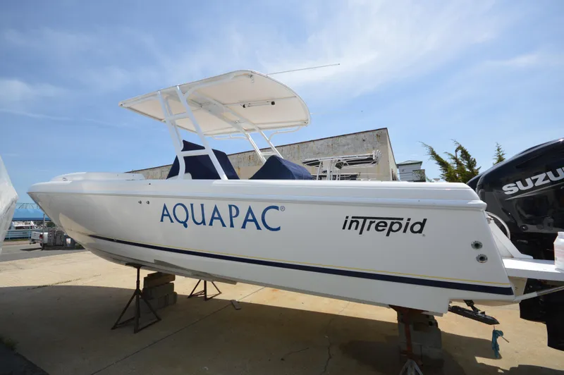 Slide: The Image of 2004 Intrepid 323 Cuddy boat with Aquapac branding, displayed on a stand outdoors. - 23