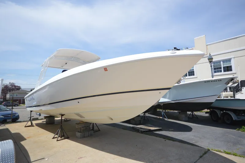 Slide: The Image of 2004 Intrepid 323 Cuddy boat on display, elevated on stands, under clear blue sky. - 3