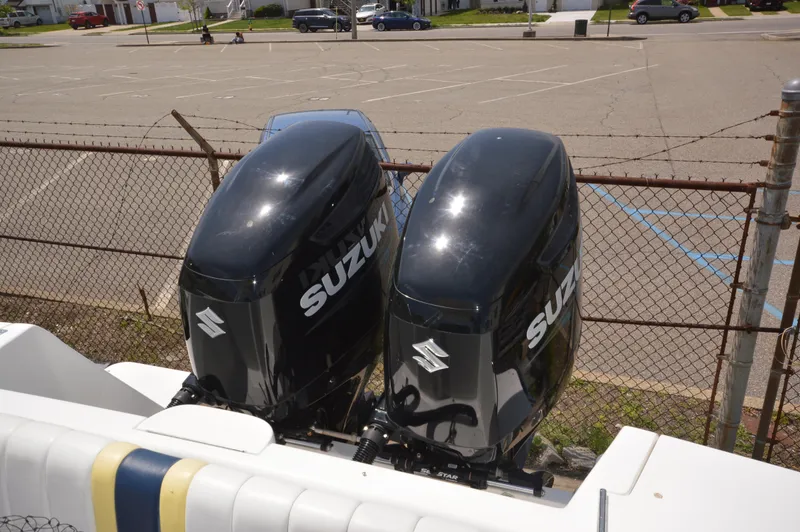 Slide: The Image of Twin Suzuki outboard motors on a 2004 Intrepid 323 Cuddy boat, parked near a fence. - 9
