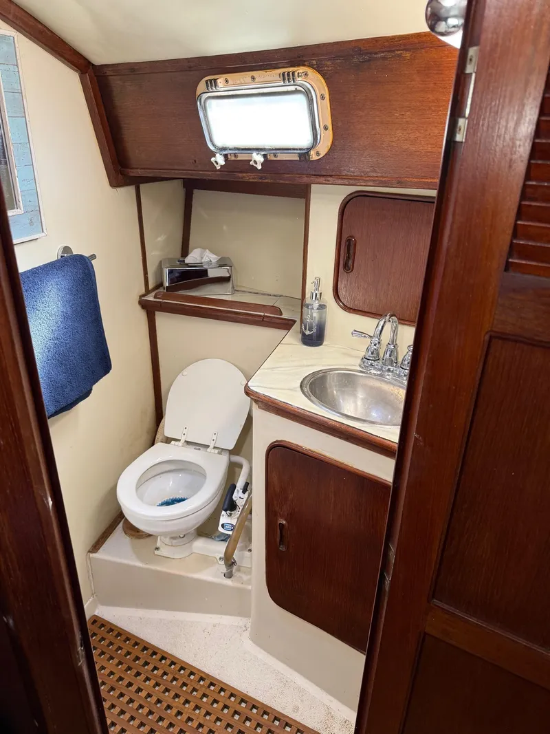 Slide: The Image of 1982 Irwin 46 yacht bathroom with wooden accents, toilet, sink, and porthole window. - 21