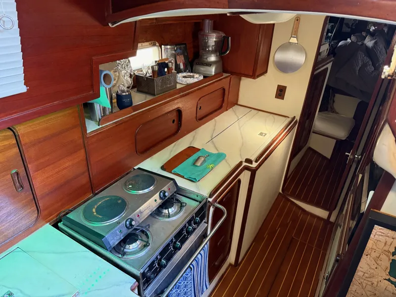 Slide: The Image of Compact kitchen in a 1982 Irwin 46 sailboat with stove, wooden cabinets, and countertop. - 24
