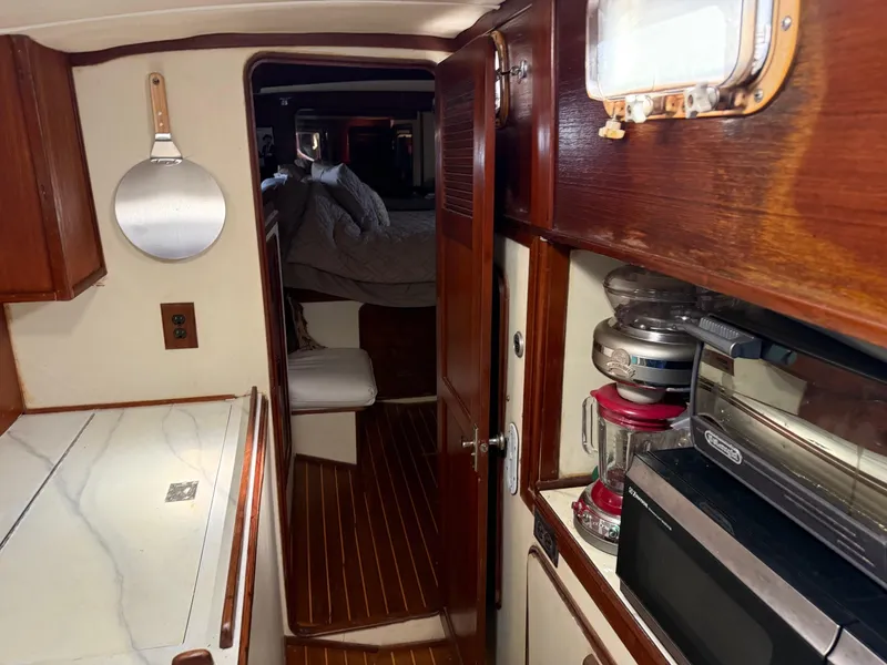 Slide: The Image of 1982 Irwin 46 yacht interior with wooden cabinetry, kitchen appliances, and cozy sleeping area. - 29