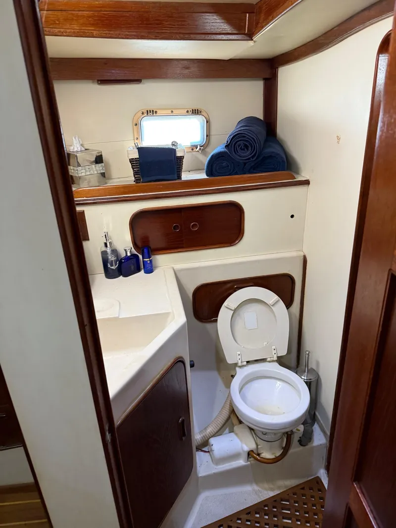 Slide: The Image of 1982 Irwin 46 yacht bathroom with wooden accents, toilet, sink, and rolled towels. - 35