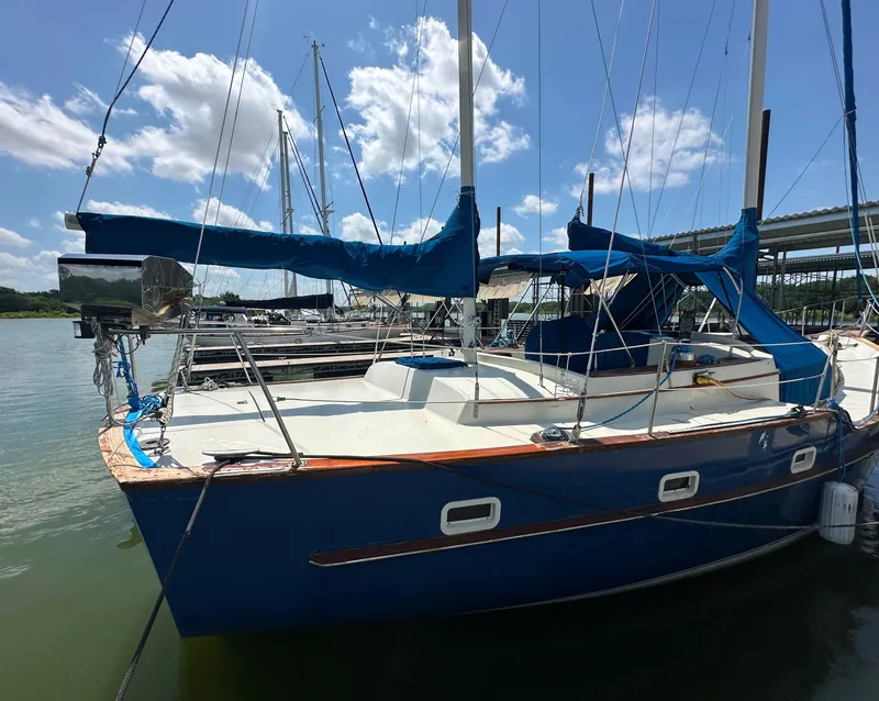 Slide: The Image of 1982 Irwin 46 sailboat docked, featuring blue hull and covered sails under a sunny sky. - 4