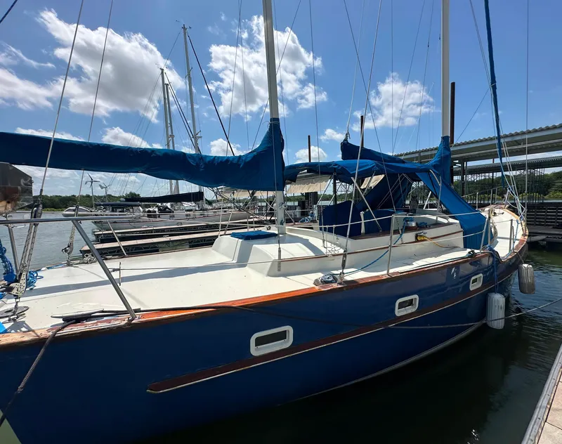 Slide: The Image of 1982 Irwin 46 sailboat docked, featuring blue hull and sails under a sunny sky. - 5