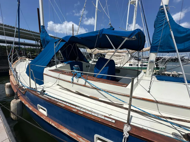 Slide: The Image of 1982 Irwin 46 sailboat docked, featuring blue covers and wooden accents under a clear sky. - 7