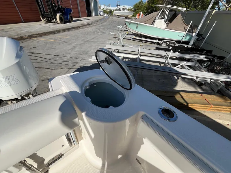 Slide: The Image of 2021 Robalo R272 Center Console boat with open storage compartment, docked near trailers. - 26