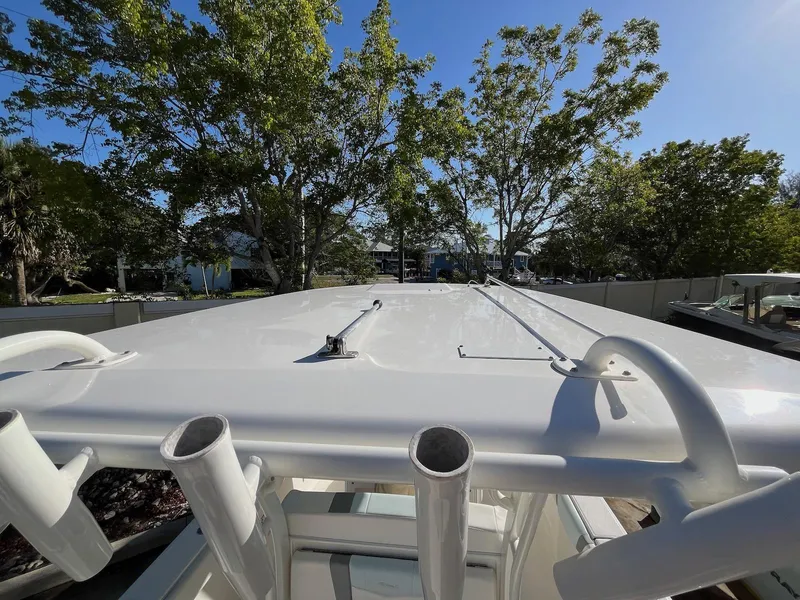 Slide: The Image of 2021 Robalo R272 Center Console boat roof with rod holders, surrounded by trees. - 7