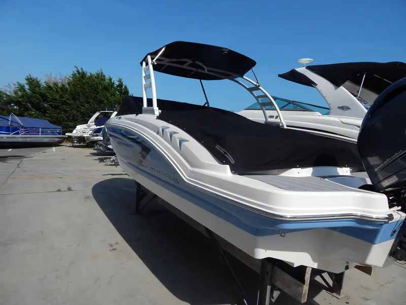 Slide: The Image of 2022 Chaparral 23 SSi OB boat with black canopy, docked outdoors on a sunny day. - 13