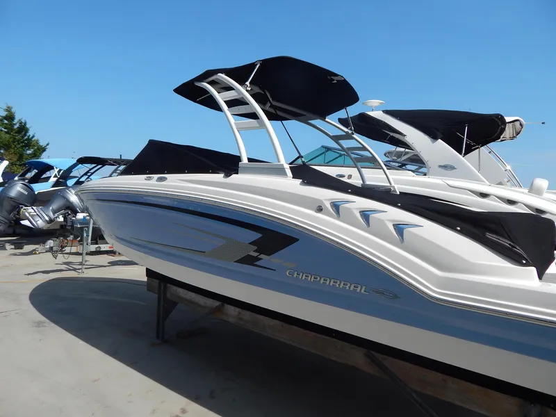 Slide: The Image of 2022 Chaparral 23 SSi OB boat with sleek design and black canopy, docked outdoors. - 14