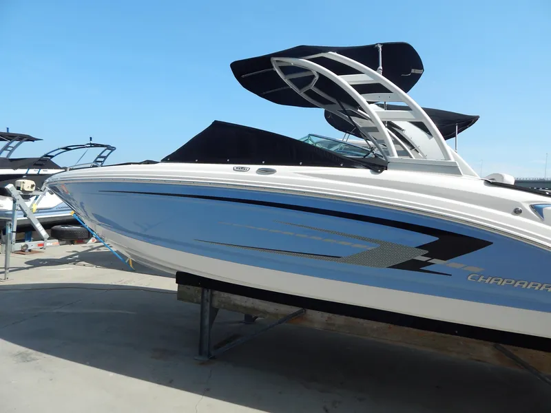 Slide: The Image of 2022 Chaparral 23 SSi OB boat with sleek design and blue accents, docked outdoors. - 15