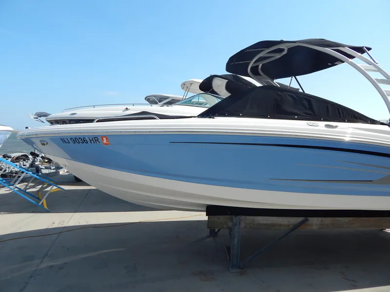 Slide: The Image of 2022 Chaparral 23 SSi OB boat with blue hull and black canopy on display. - 16