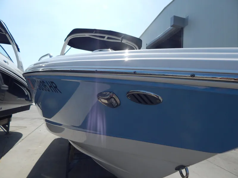 Slide: The Image of 2022 Chaparral 23 SSi OB boat with blue hull, docked outdoors. - 31