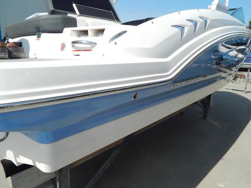 Slide: The Image of 2022 Chaparral 23 SSi OB boat, white and blue hull, docked on a sunny day. - 6