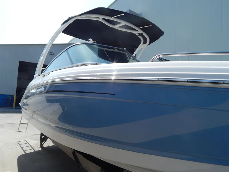 Slide: The Image of 2022 Chaparral 23 SSi OB boat with sleek blue hull and canopy, docked outdoors. - 9