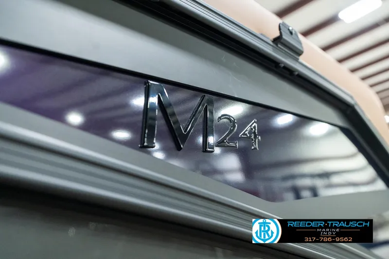 Slide: The Image of 2025 Bennington 24 MSB boat with M24 logo, indoor setting, Reeder-Trausch branding. - 48