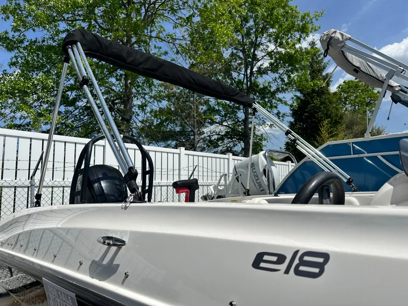 Slide: The Image of 2018 Godfrey Hurricane 188SD boat with canopy, parked outdoors under a clear sky. - 2
